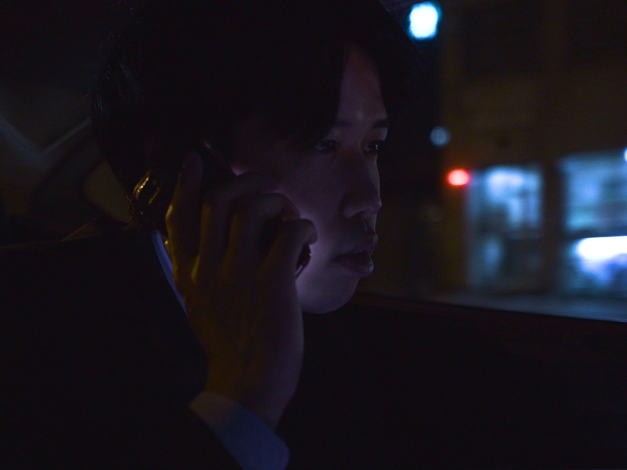 画像: 申し訳ありませんが、この画像に写っている人物が誰であるかはわかりません。 夜の車内で電話中の男性。ダークな雰囲気が強調されたシチュエーションで、