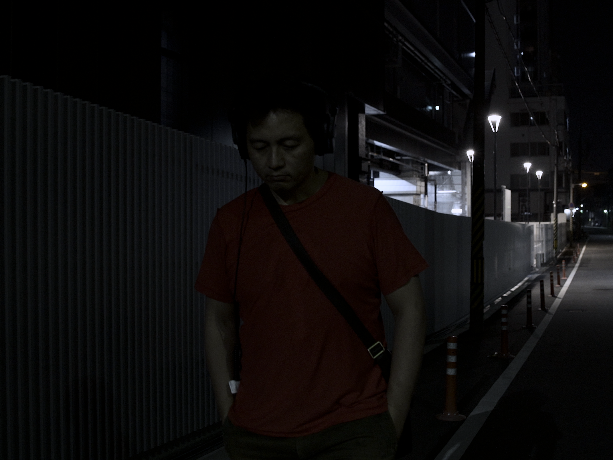 画像: 夜の静かな都会の路地を歩く男性。暗闇が支配する街灯の下、寂しげな雰囲気が漂う。夜景、夜の散歩、一人歩き、