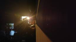 画像: 画像には、屋内の暗いシーンと、窓から差し込む強い日差しが写っています。太陽の光が、壁や室内のオブジェクトに影を落とし、