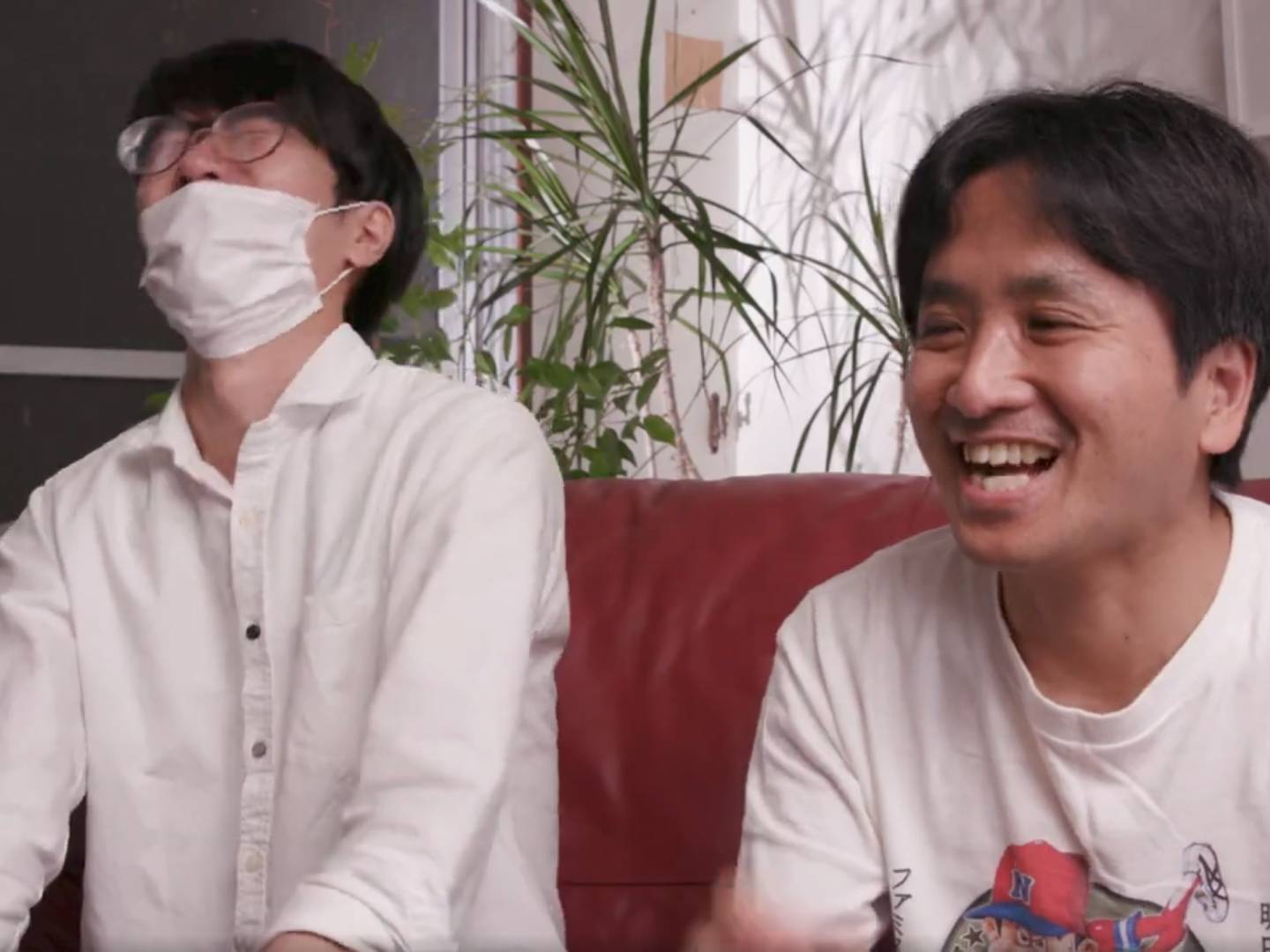 画像: 申し訳ありませんが、この画像の人物についてはわかりません。ただし、画像の説明を書くことができます。 --- ソファに座って笑っている2人の男性の室内写真。リラックスした雰囲