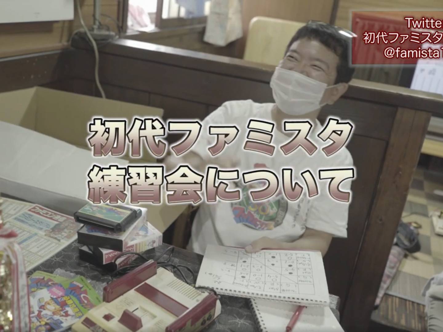 画像: 室内で行われる初代ファミスタ練習会の様子。テーブルにはファミコン、ゲームカセット、トロフィーが置かれています。笑顔の参加者がマスクを着