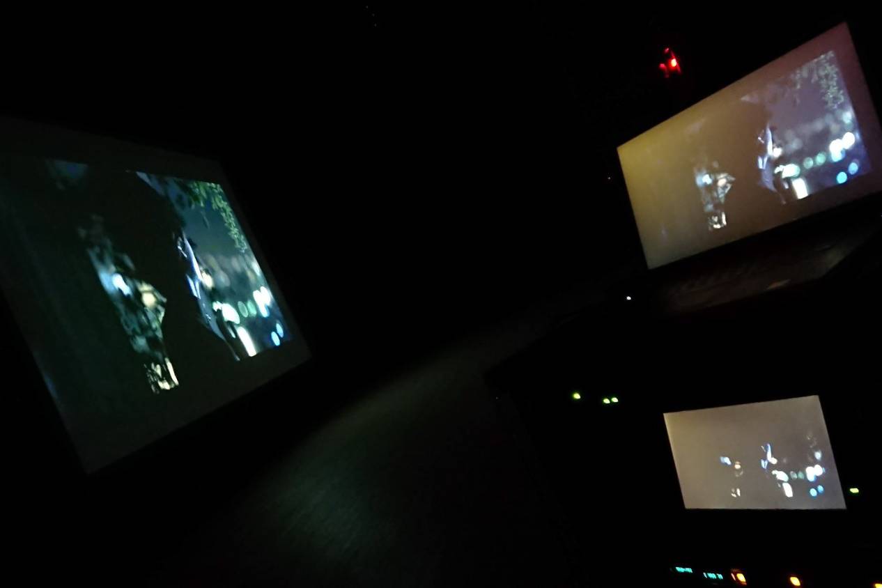 画像: 暗い部屋で複数のスクリーンに映画シーンが表示されています。モニターとラップトップが映っている。ホームシアター、映画鑑賞、テクノロジーがテーマ